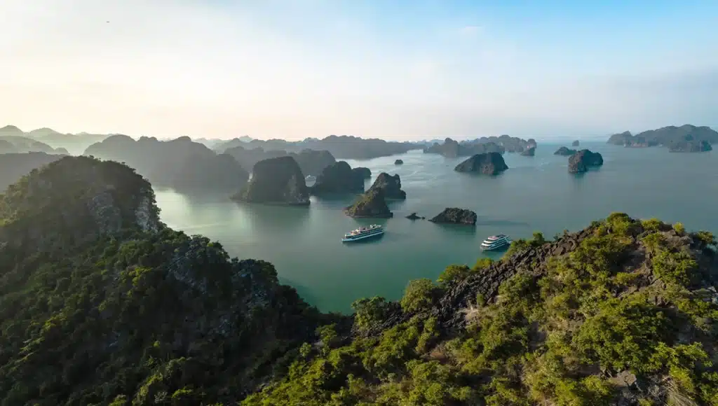 Vue panoramique aérienne sur les pitons karstiques verdoyants et les bateaux de croisière naviguant sur les eaux calmes de la baie de Lan Hạ.